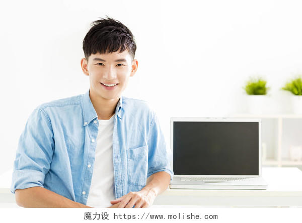 与笔记本电脑的亚洲年轻男人微笑着